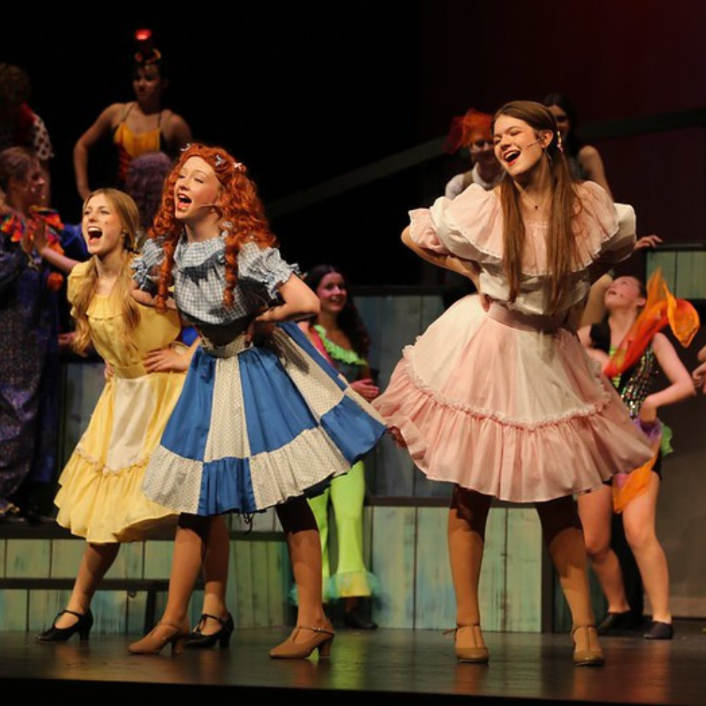 Three cast members on stage singing