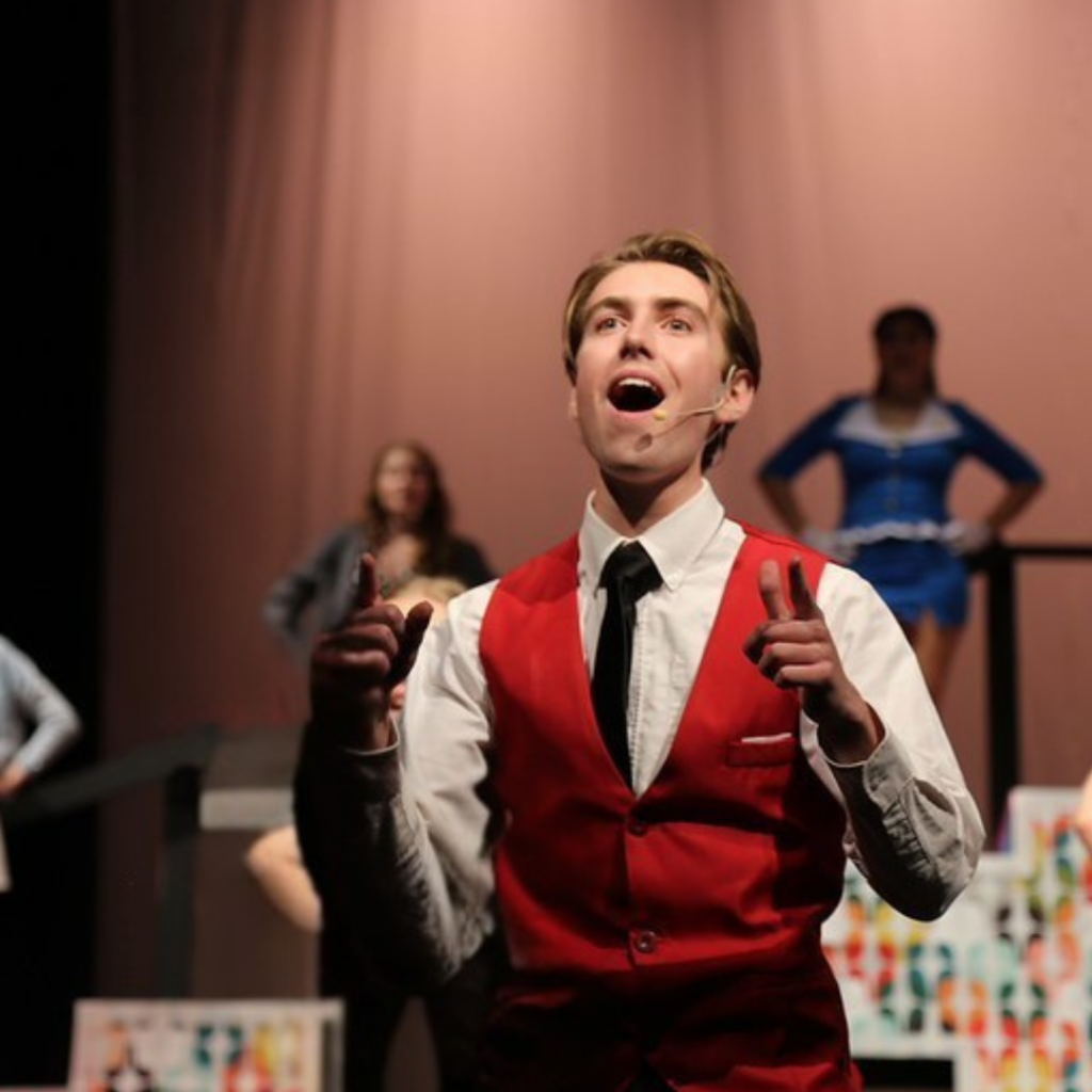 Male character singing on stage